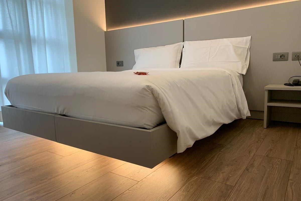 A modern bedroom with a bed, bedside table, and a nightstand.