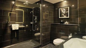 Un baño moderno con ducha de vidrio, inodoro separado y lavamanos.
