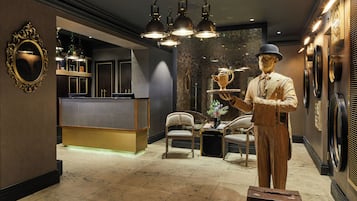A reception area with a counter, chairs, a statue, and a decorative mirror.