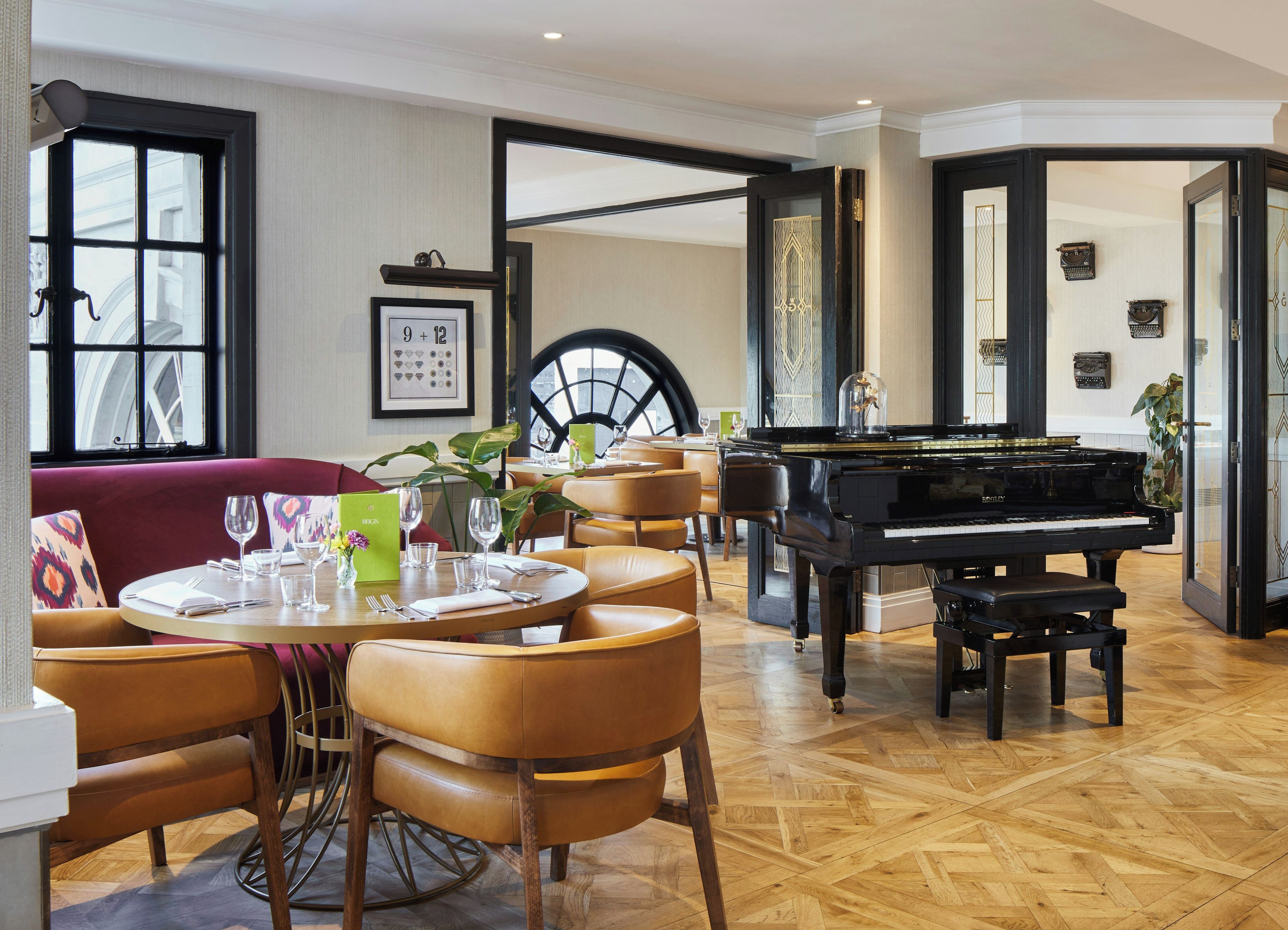 A dining area with a piano, round tables, and chairs.