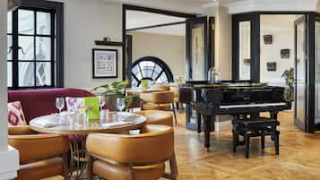 A dining area with a piano, round tables, and chairs.