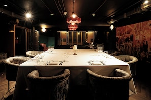 A dining room with a long table set for a meal, surrounded by upholstered chairs. - The Rex – Formerly Hotel Gotham (Manchester)