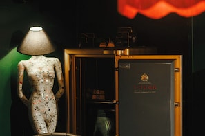 Un maniquí con una lámpara, una caja fuerte y una flor roja.