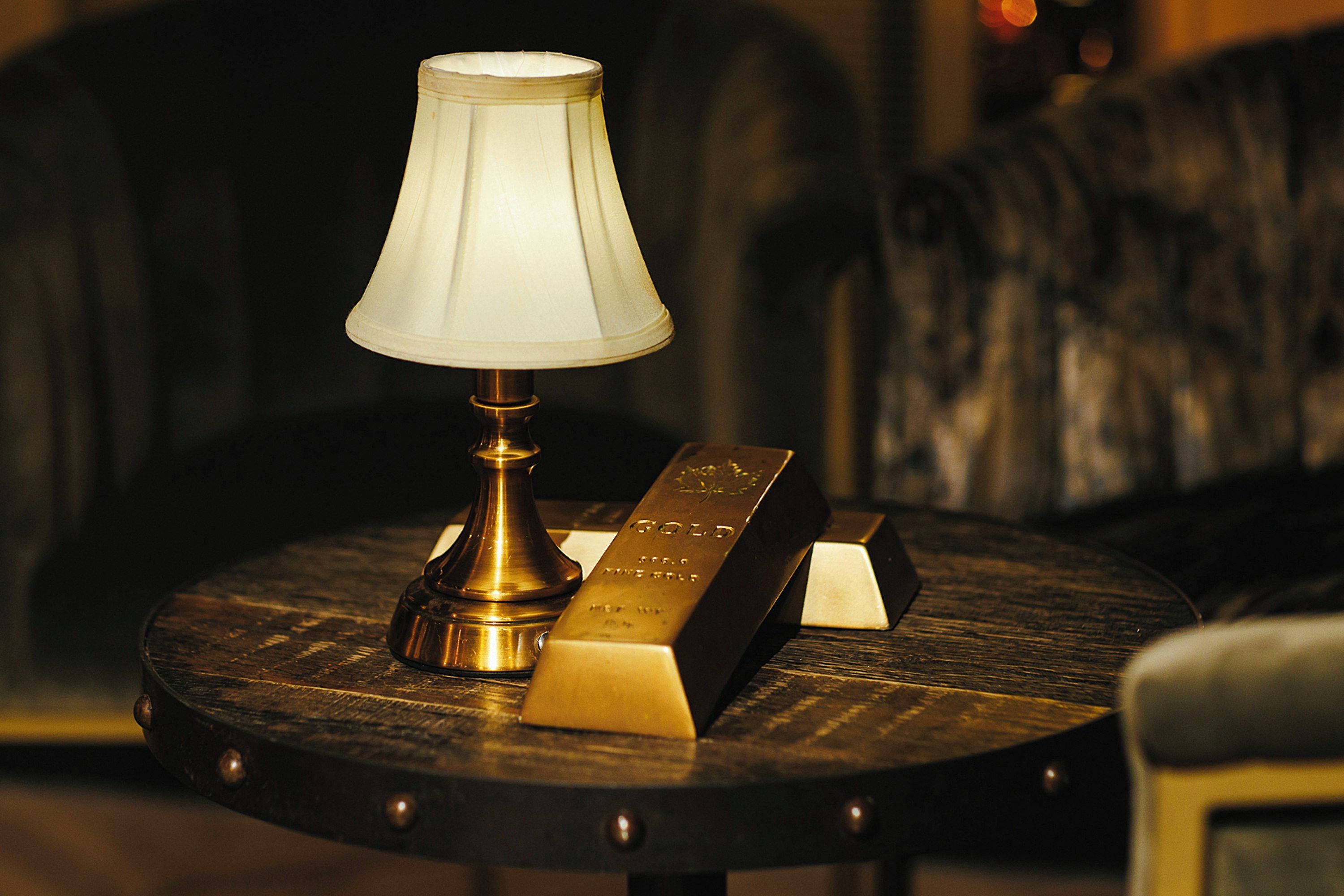 Une table ronde avec une lampe, deux lingots d’or et une chaise.