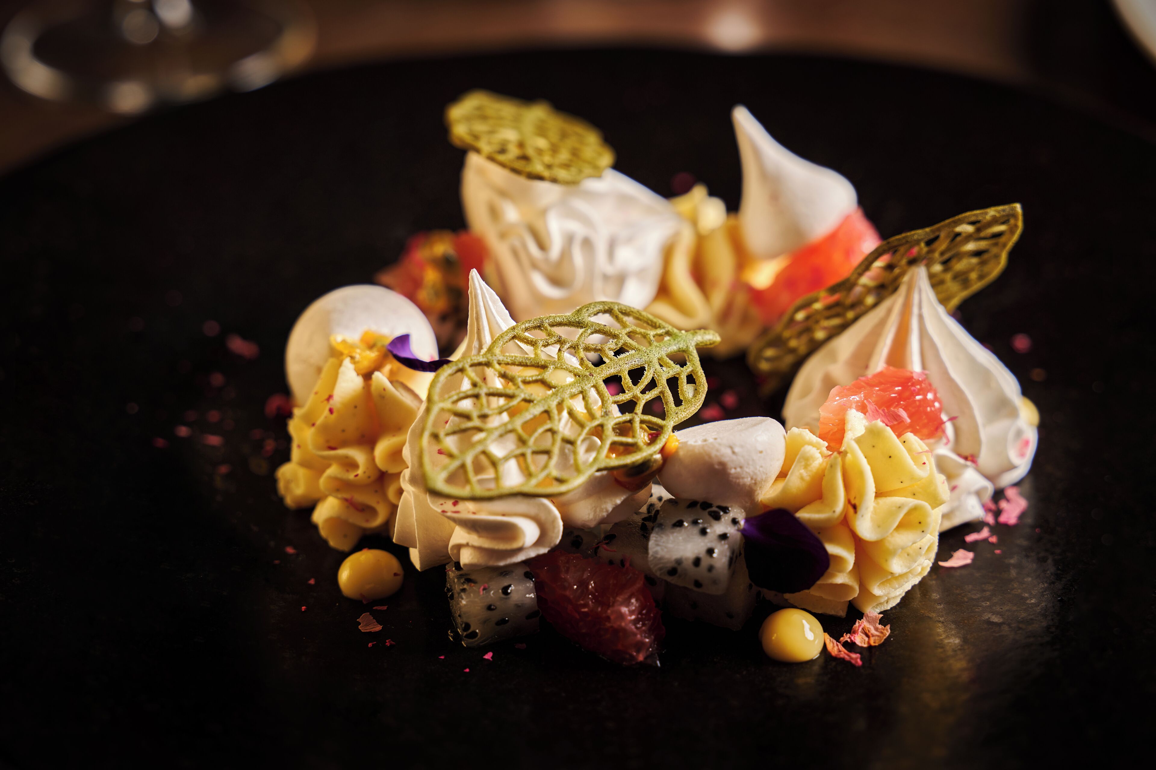 A dessert with various components on a dark plate.