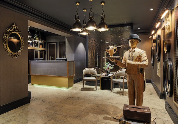 A reception area with a counter, chairs, a statue, and a decorative mirror.