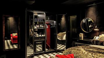 A hotel room with a checkered floor, a red sofa, a wardrobe with a mirror, and a bed with patterned bedding.