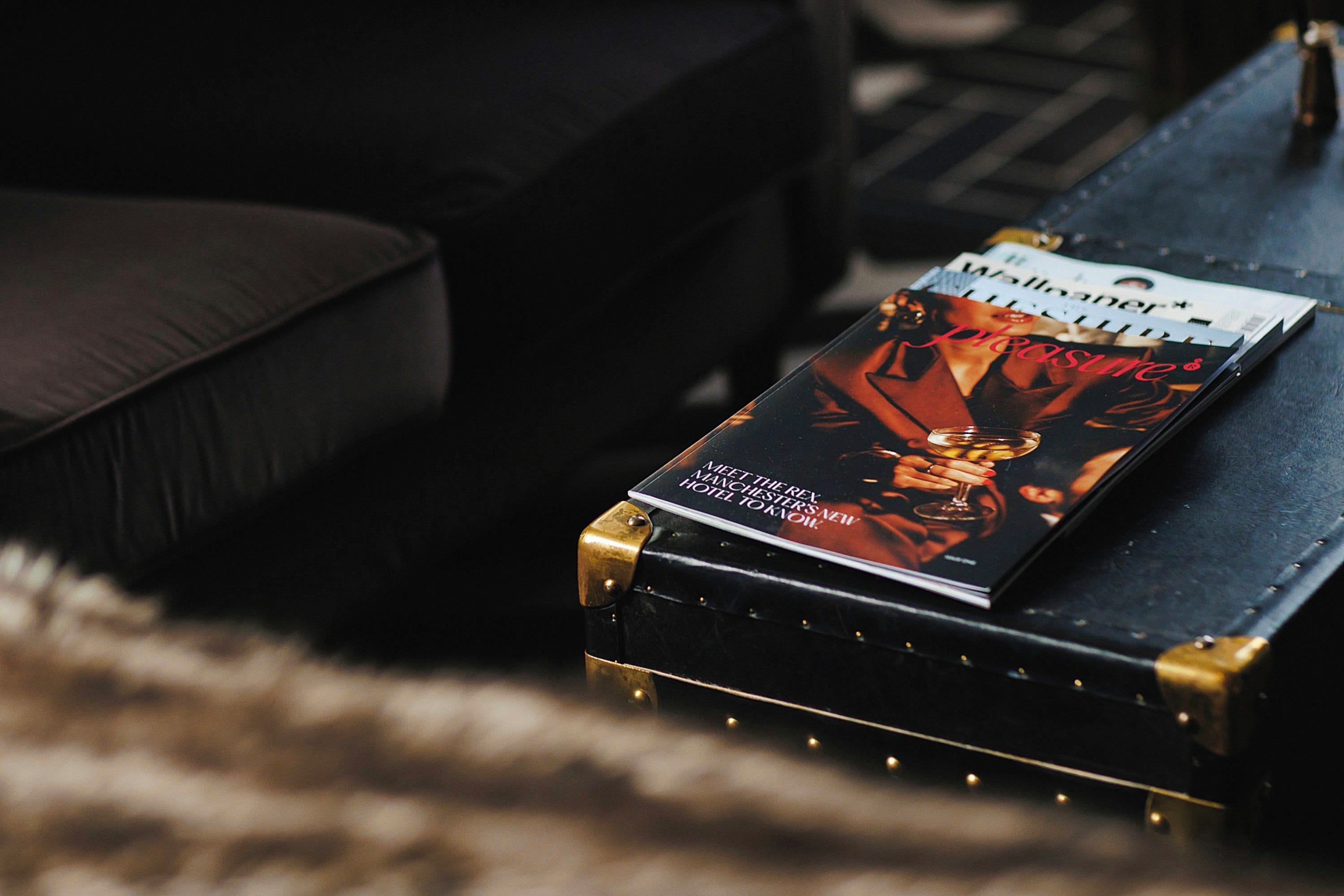 A magazine on a black suitcase with gold accents, placed on a dark surface.