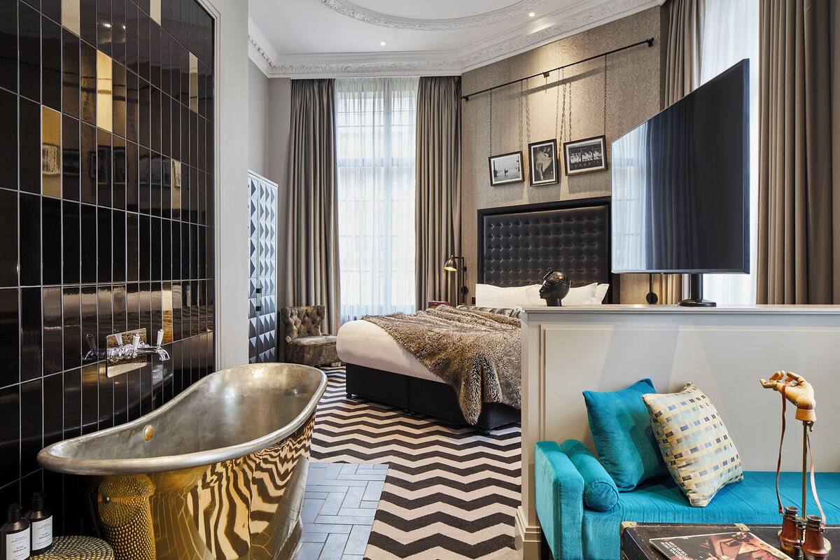 A modern bedroom with a large bed, a bathtub, and a sofa.