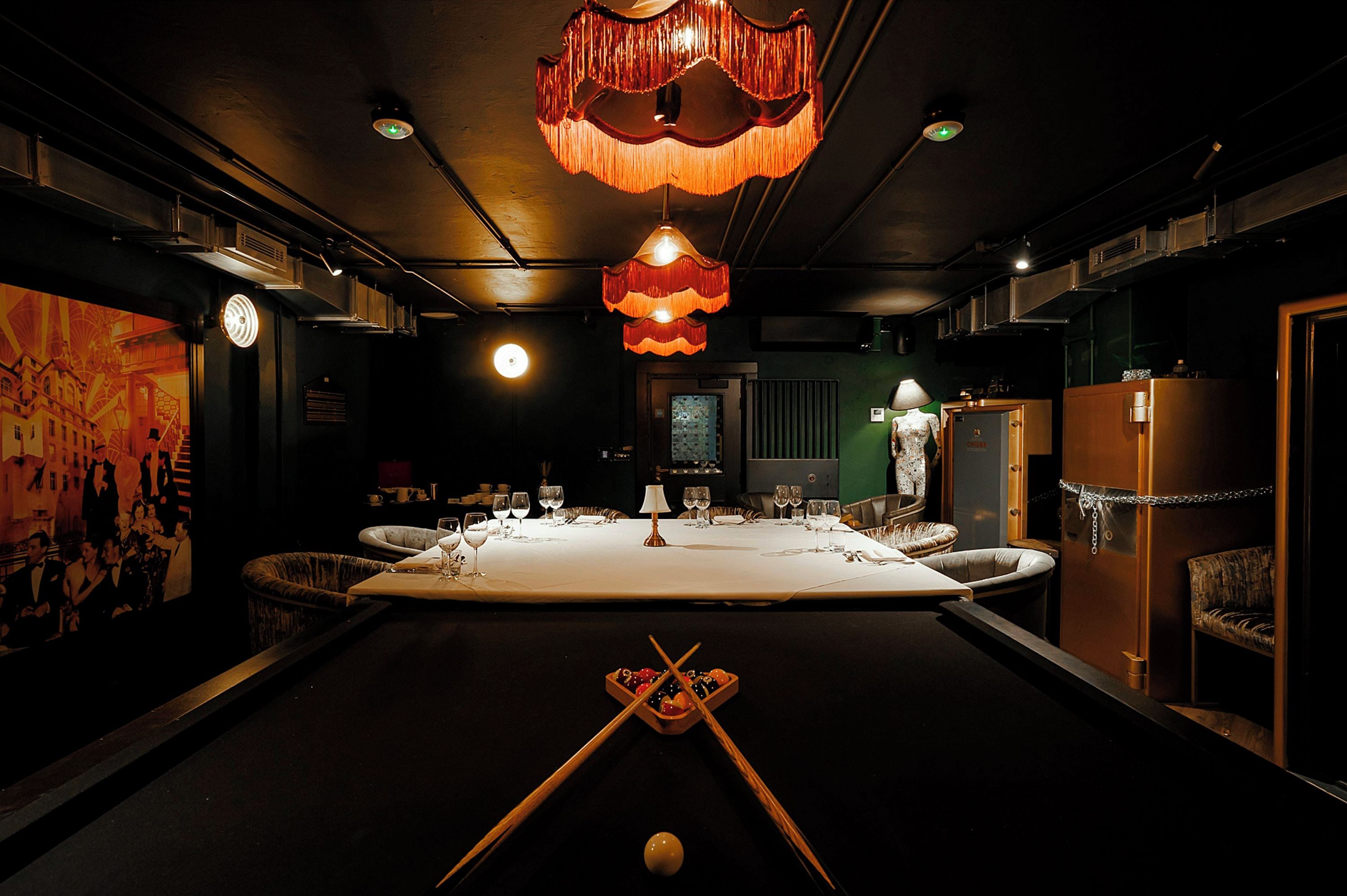 A dimly lit room with a pool table, billiard cues, and a billiard ball.
