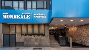 Entrada de hotel con un letrero azul que dice "HOTEL MONREALE EXPRESS GLICÉRIO CAMPINAS".