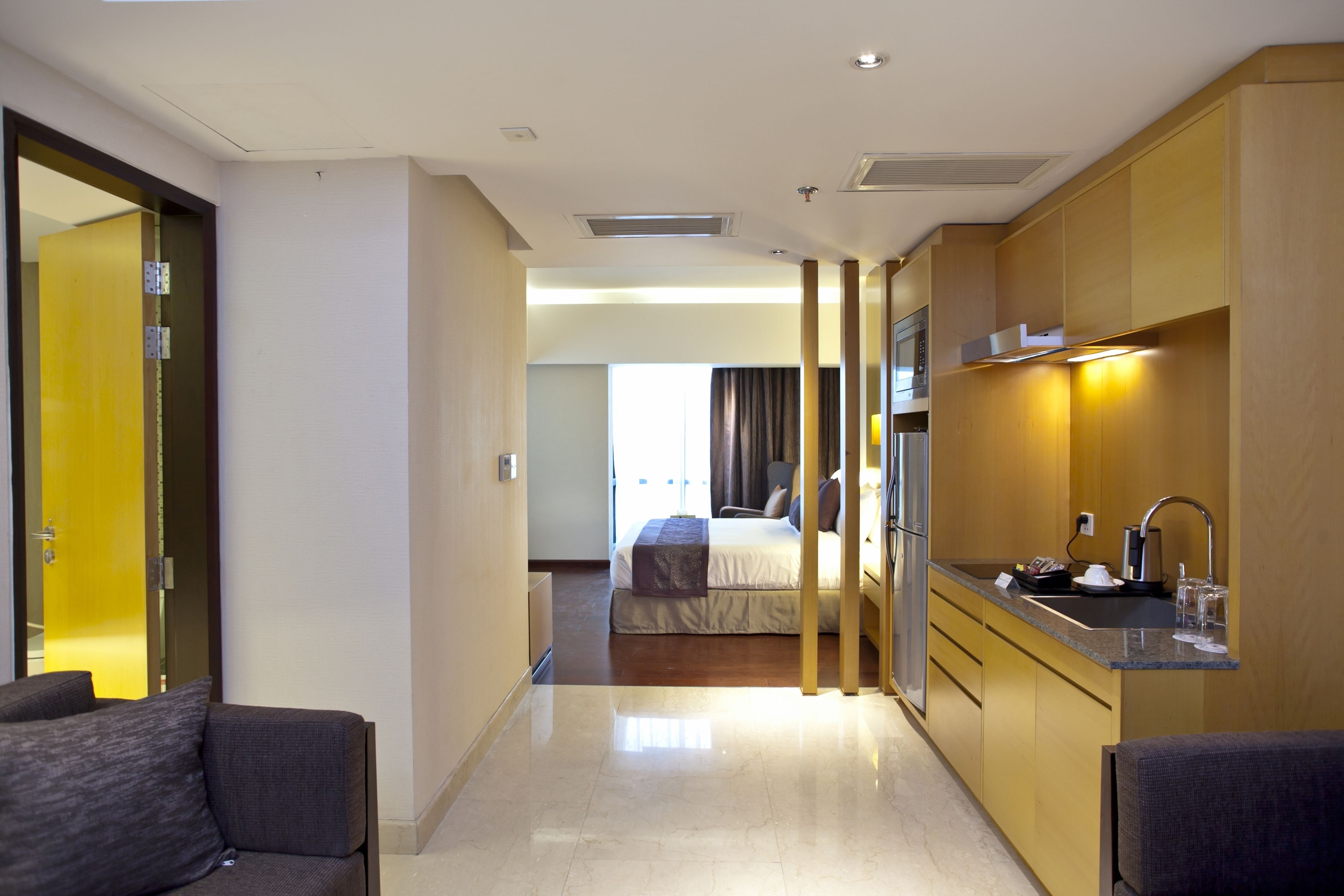 Una habitación de hotel con cama, una kitchenette pequeña y un área de descanso con dos sillas.