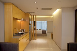 A compact hotel room with a kitchenette, a bed, and a bathroom.