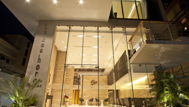 A modern hotel lobby with a glass facade, a staircase, and seating areas. - Lakeshore Banani (Dhaka)
