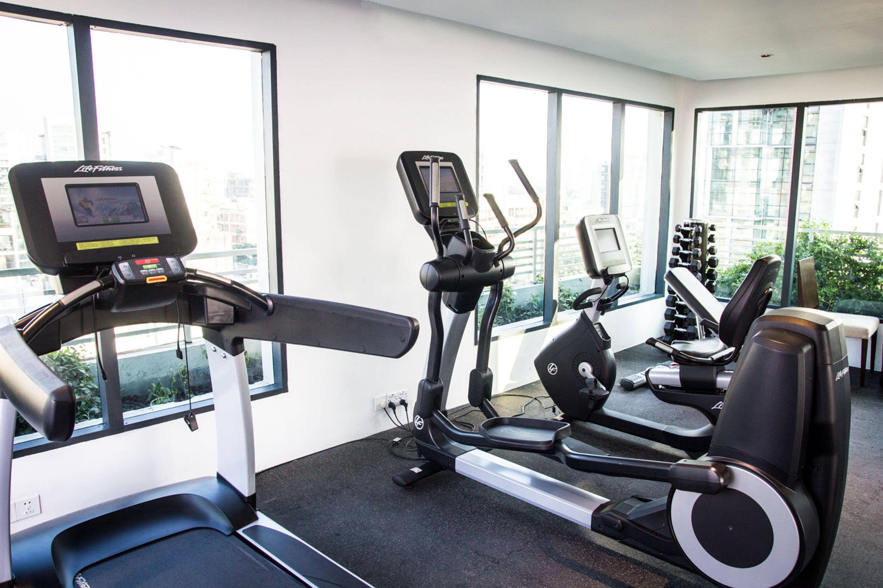 A gym with treadmills, elliptical machines, and dumbbells.