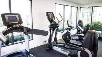 A gym with treadmills, elliptical machines, and dumbbells.