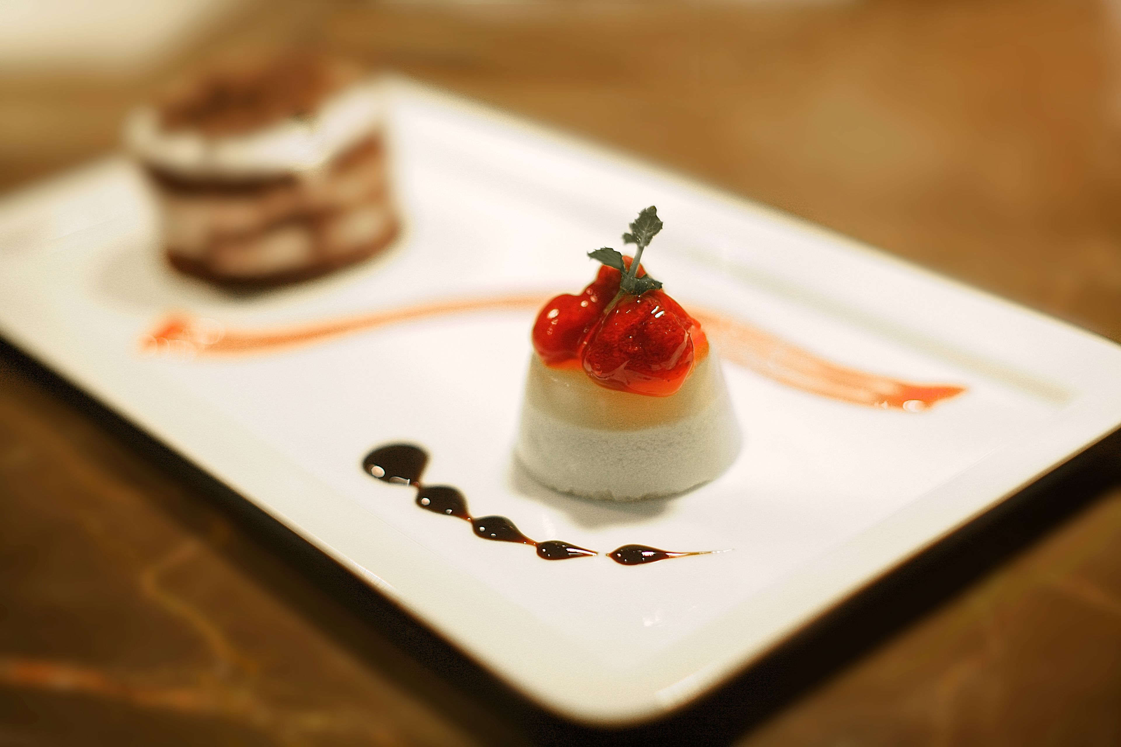 Un dessert servi dans une assiette blanche, nappé d’une sauce et agrémenté d’une petite garniture.