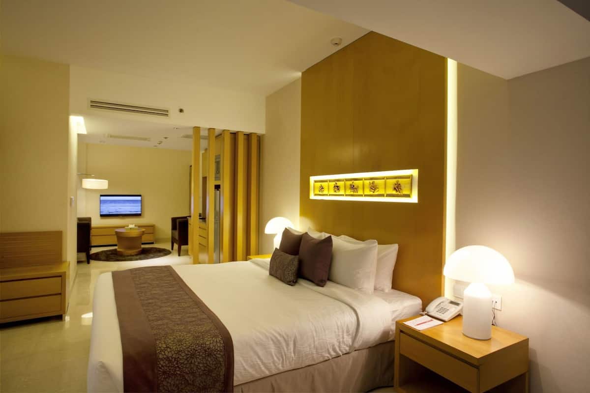 A hotel room with a bed, bedside lamps, a TV, a desk, and a chair.