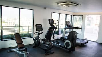 A gym with cardio machines and a bench, large windows with a city view, and a clean, modern design.