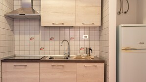 Een keuken met lichte houten kastjes, een roestvrijstalen spoelbak en een witte koelkast.