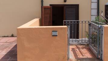 Un immeuble à la façade jaune, doté d’une entrée fermée par un portail et d’un balcon orné d’une rambarde en métal.