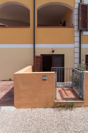 Un immeuble à la façade jaune, doté d’une entrée fermée par un portail et d’un balcon orné d’une rambarde en métal.