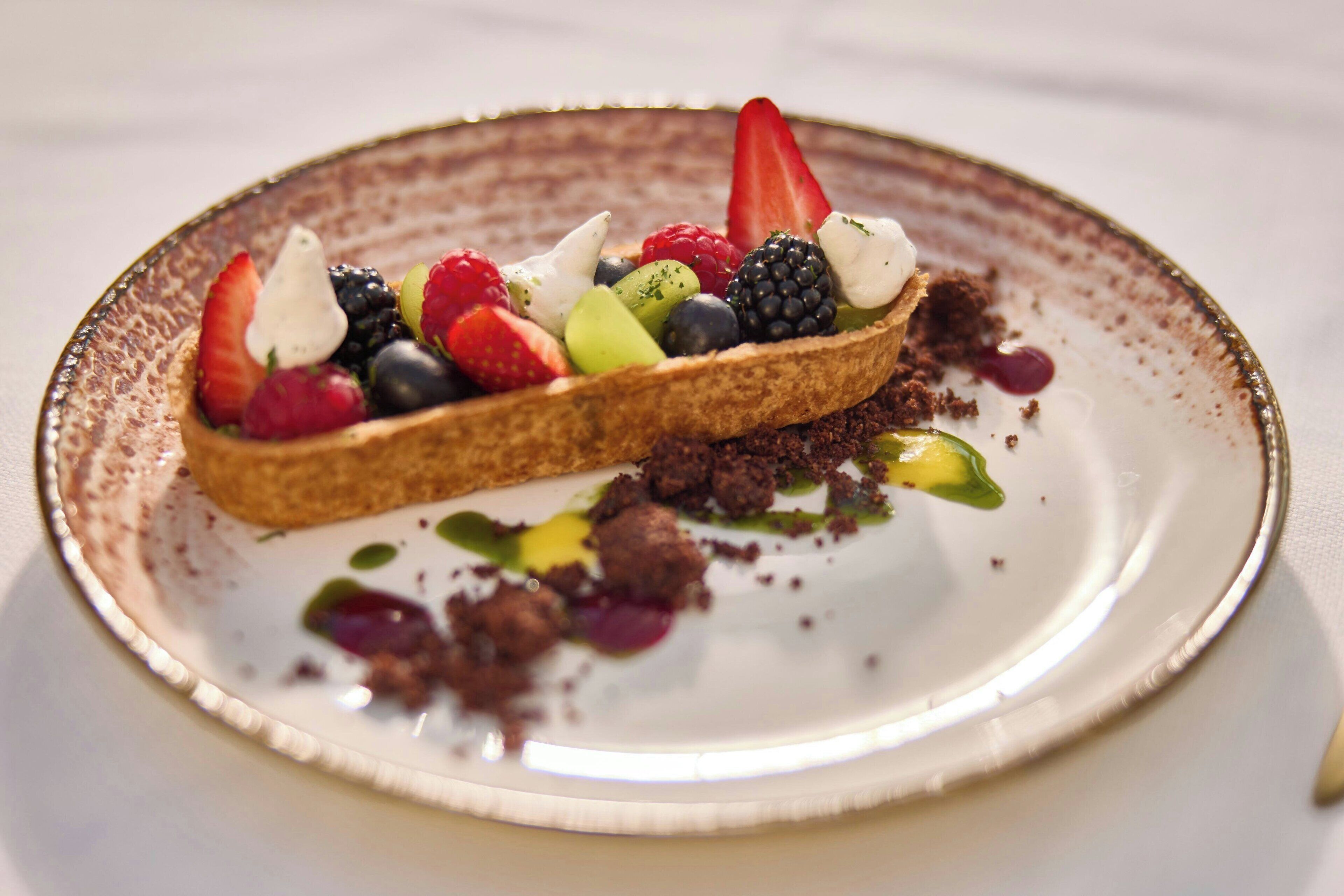 Un postre con fruta y chocolate sobre un plato.