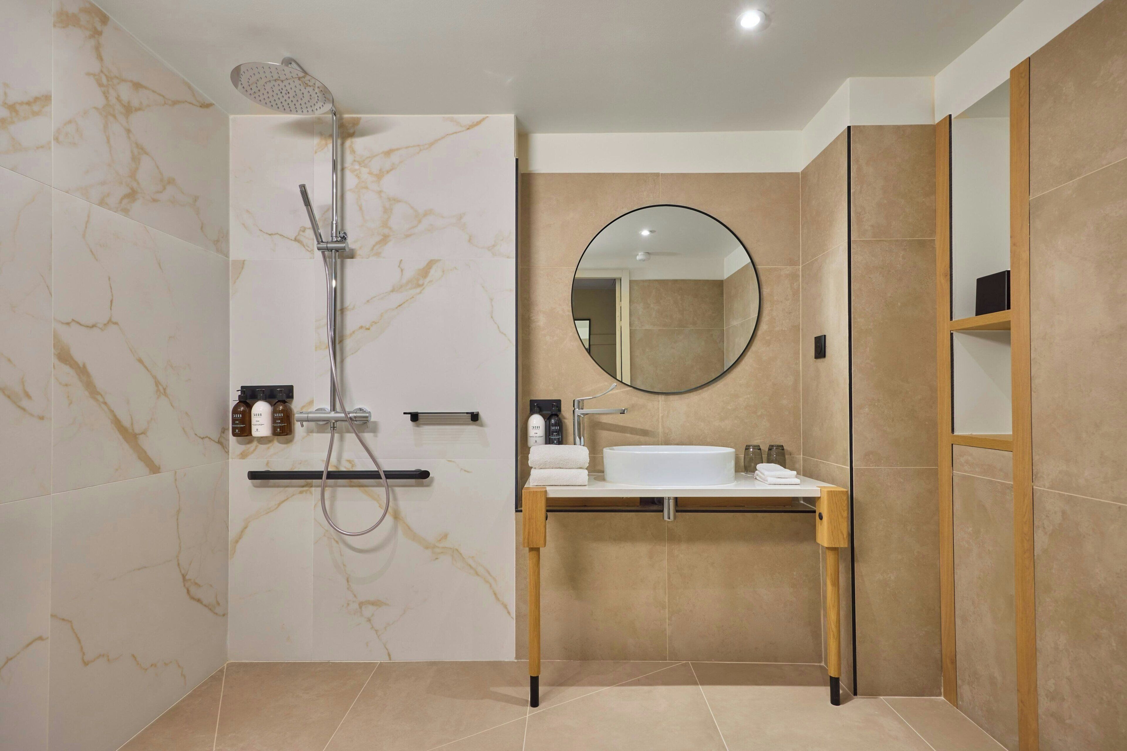 Un baño moderno con ducha, lavabo y espejo.