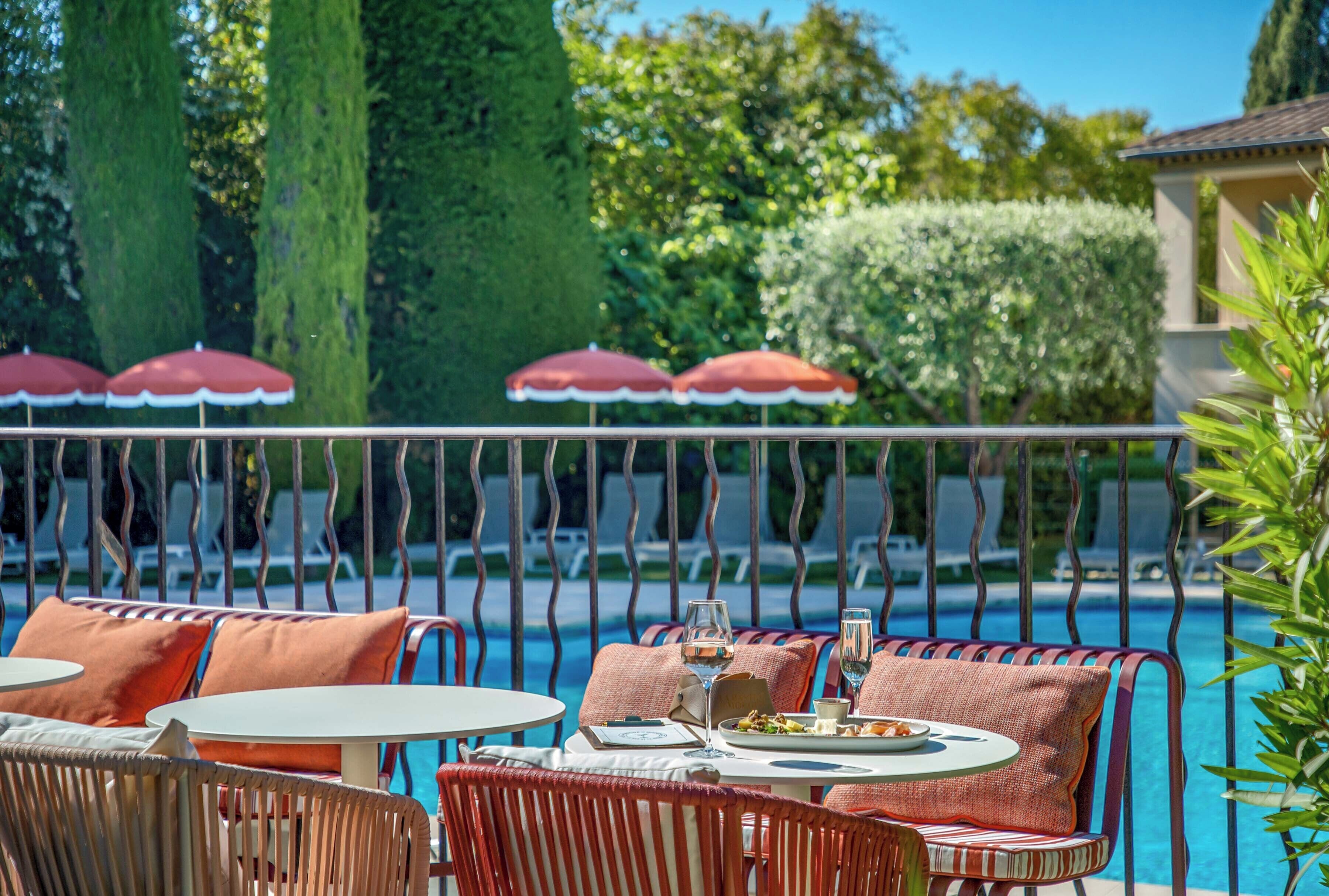 A poolside area with lounge chairs, umbrellas, and dining tables.