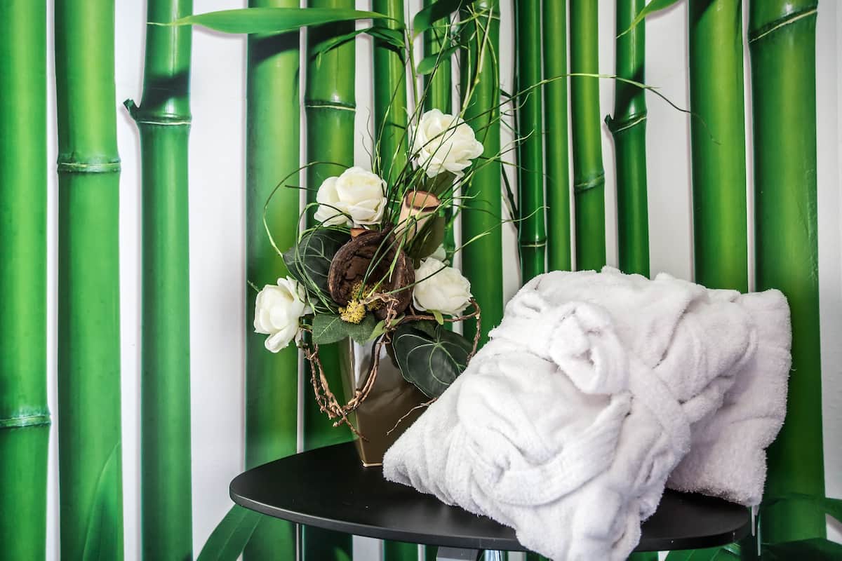 A bathroom with a black sink, a white towel, and a vase with white flowers.
