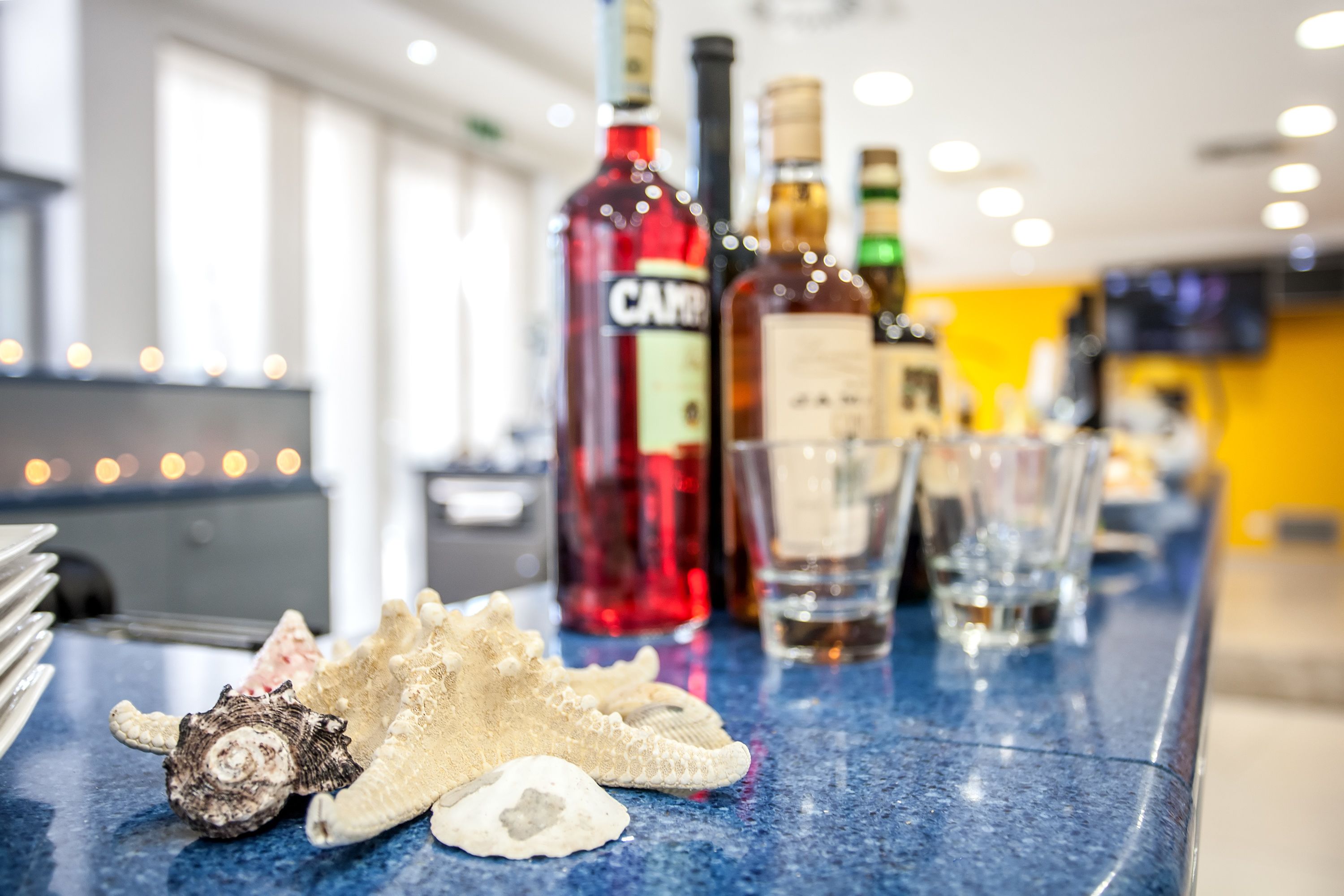 A bar area with bottles of liquor, glasses, and a decorative shell on a blue countertop.