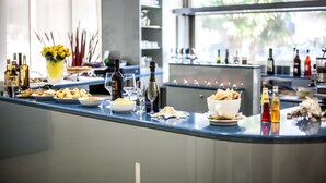 Zona de bar bien iluminada con diferentes botellas, vasos y una variedad de aperitivos.