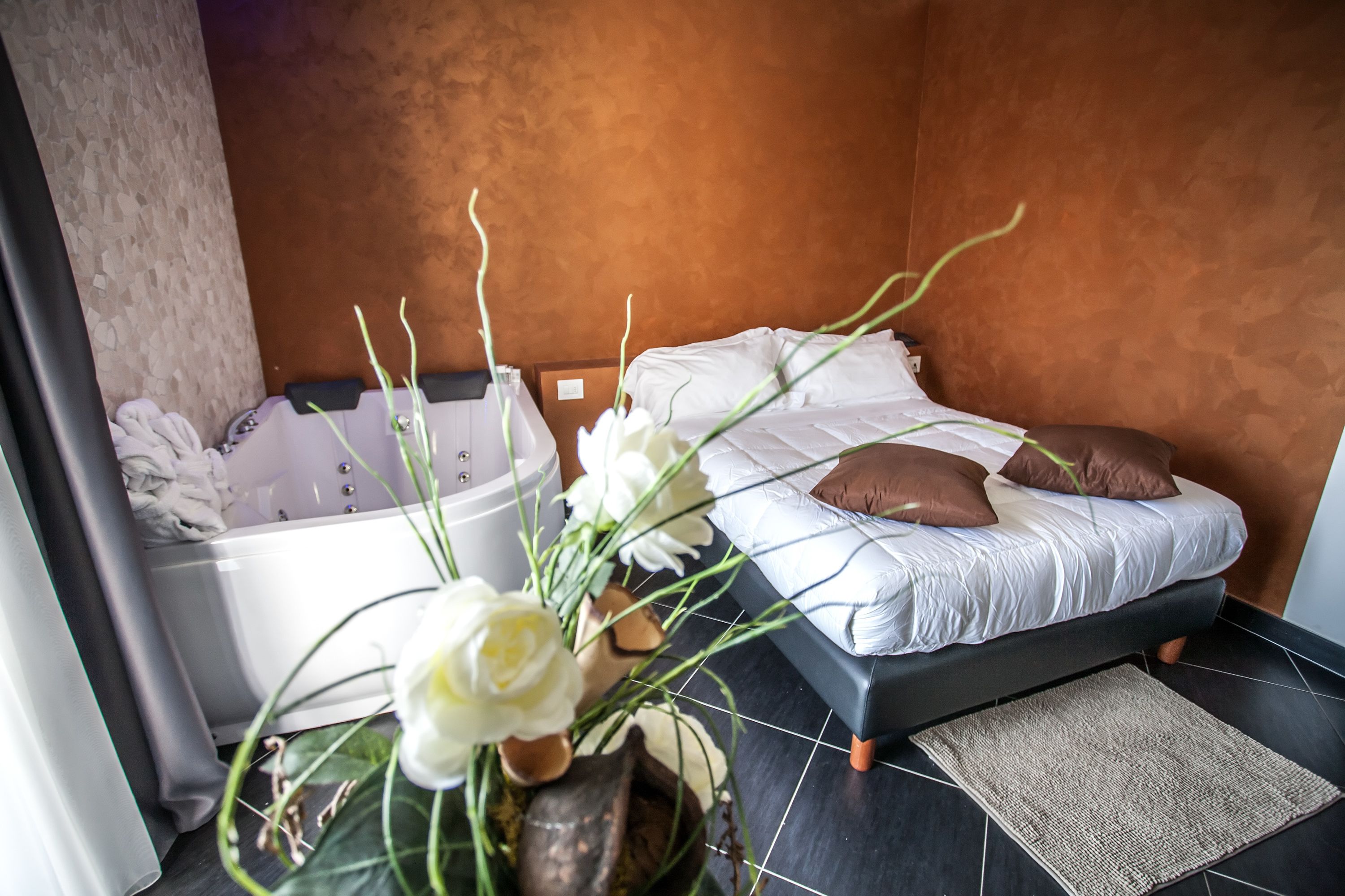 Een moderne badkamer met een badkuip, een douchegedeelte en een bed met een donkere hoofdeinde.