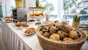 Una mesa de buffet con diversos alimentos, como pan, frutas y pasteles.