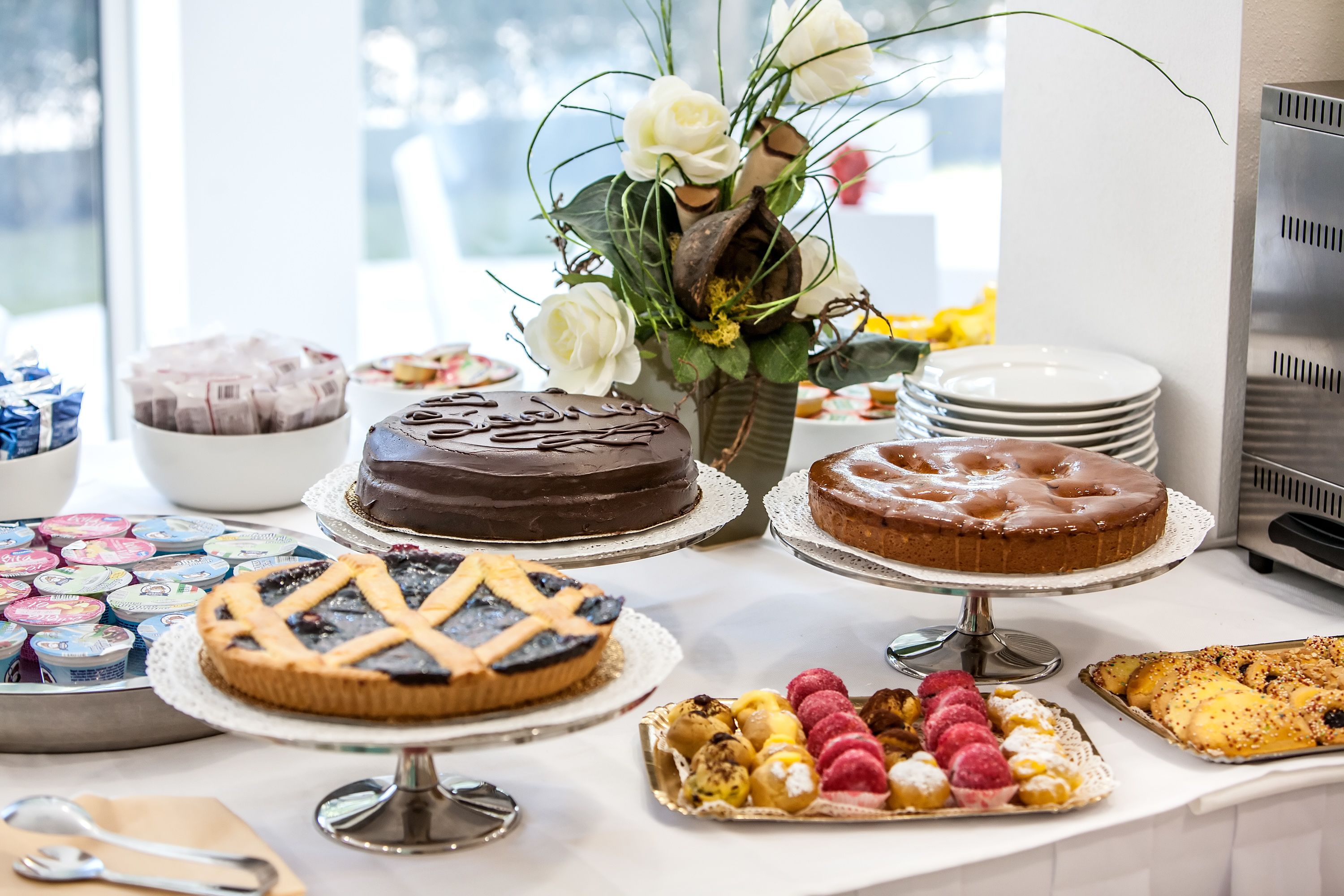 A buffet table with various desserts and pastries, including cakes and pies, arranged on stands.