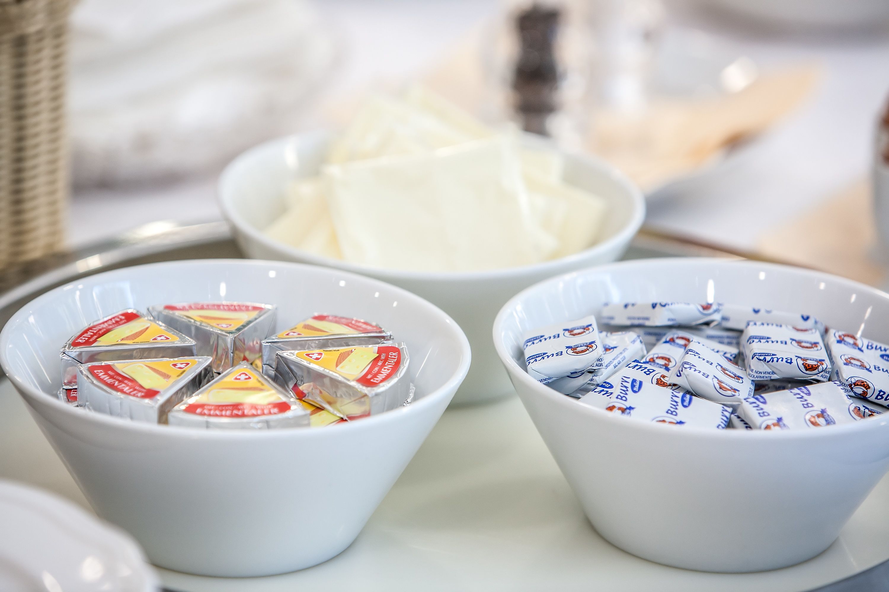 Two white bowls containing packaged food items, one with yellow and red packaging and the other with blue and white packaging.