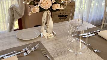 Una mesa de comedor dispuesta con un florero, velas y copas de vino vacías.