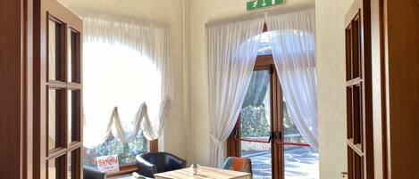 A room with a table, chairs, and a view of the outdoors. There are signs indicating 'Sala Studio' and 'Sala Smart Working'.