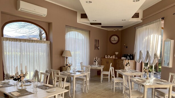 A dining area with multiple tables and chairs, a clock on the wall, and a cabinet with bottles. - Park Hotel Imperatore Adriano (Guidonia Montecelio)