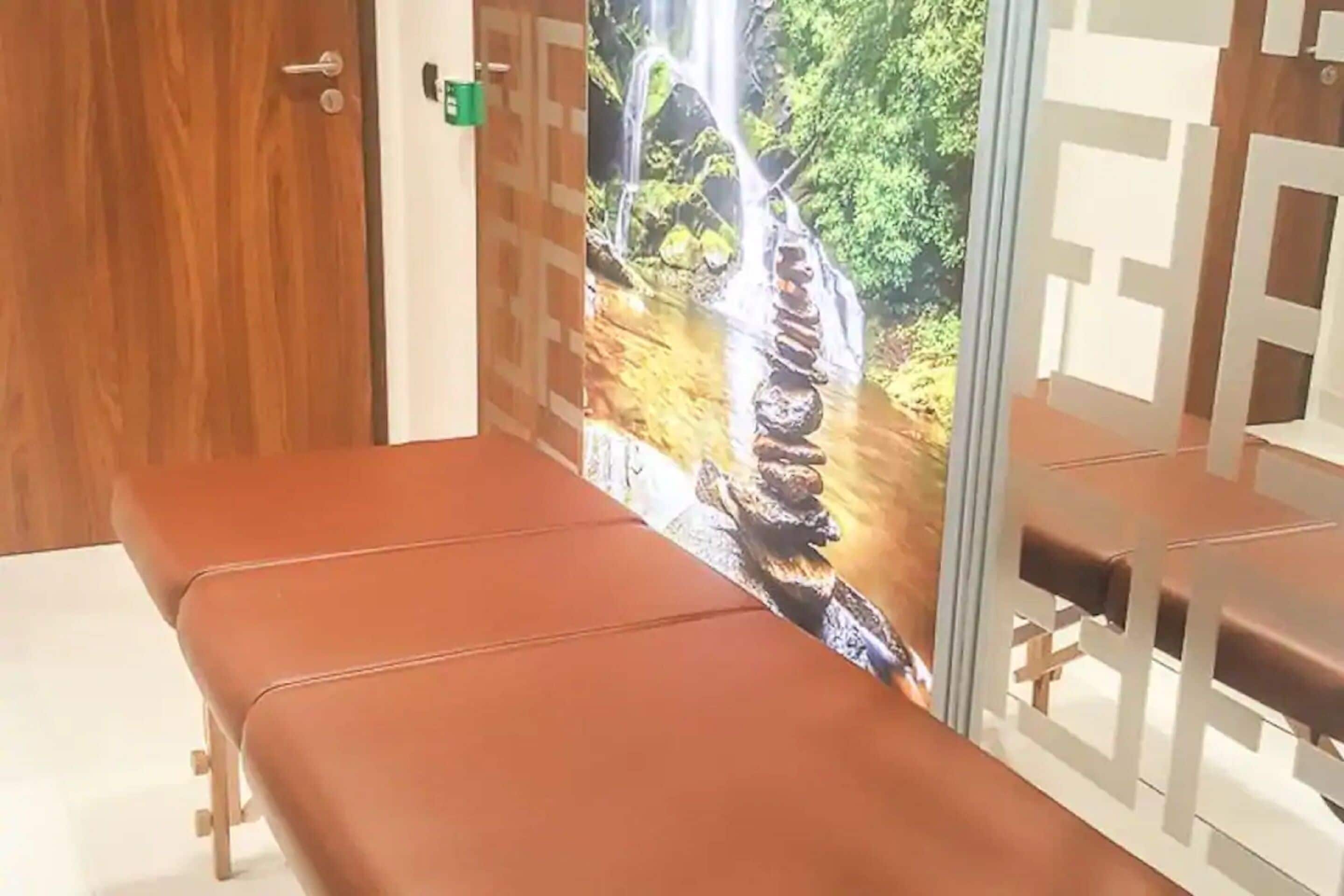 A room with a wooden door, a bench, and a wall with a waterfall mural.