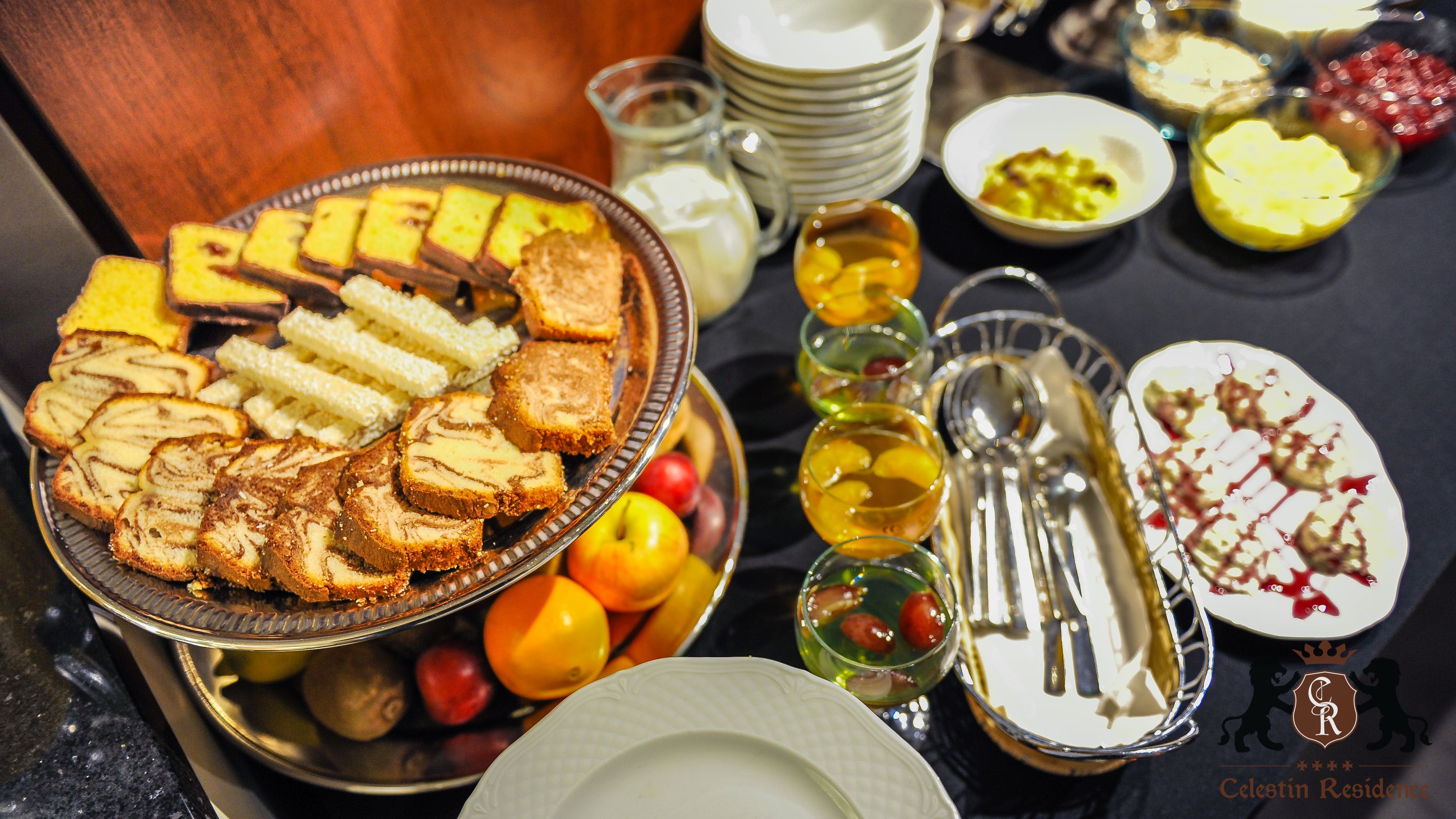 A buffet table with various food items, including bread, fruits, and desserts.