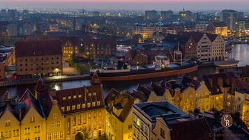 A historic cityscape with traditional architecture, a river, and a large ship docked at the harbor.
