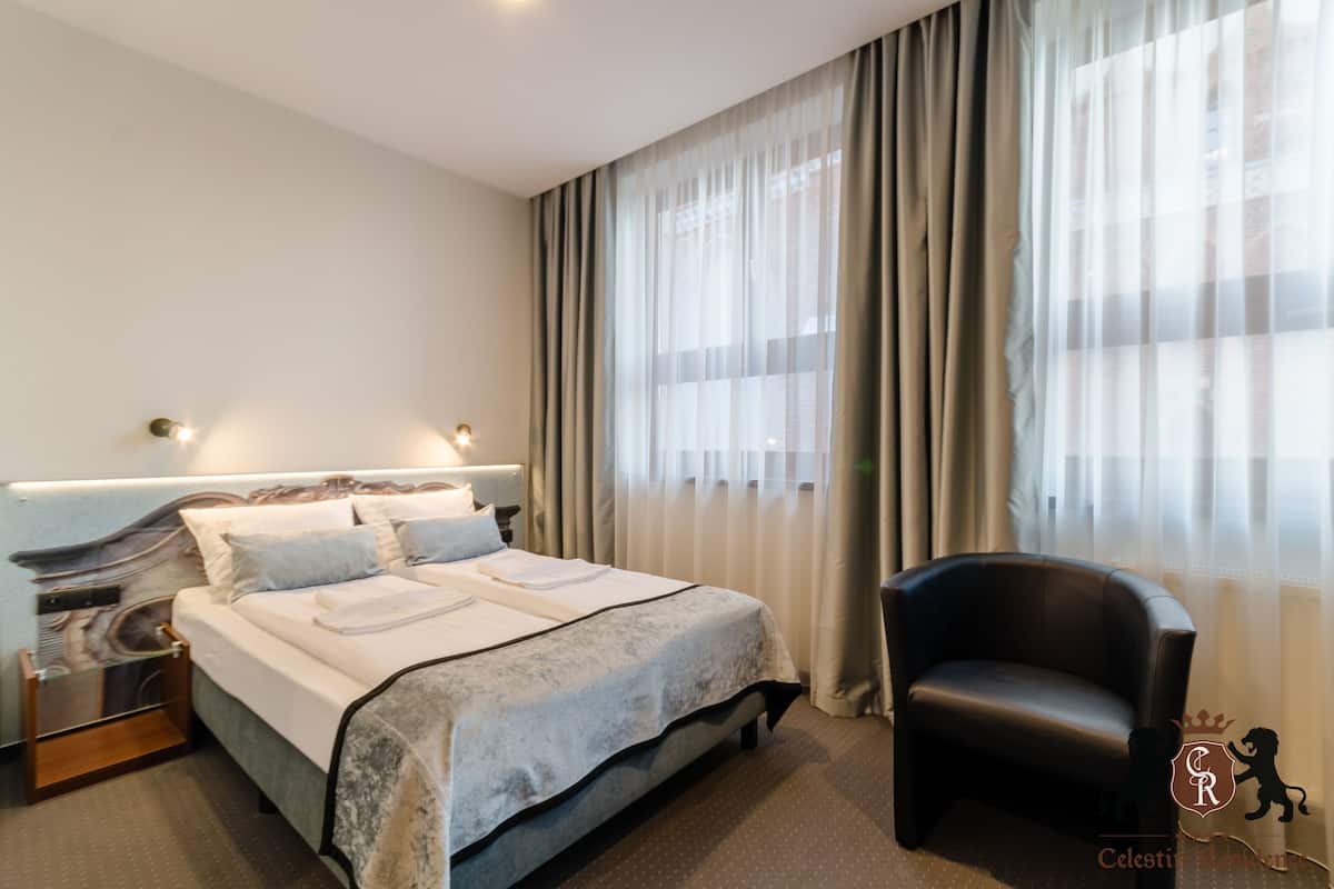 A hotel room with a large bed, a chair, and a nightstand.