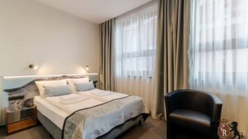 A hotel room with a large bed, a chair, and a nightstand.