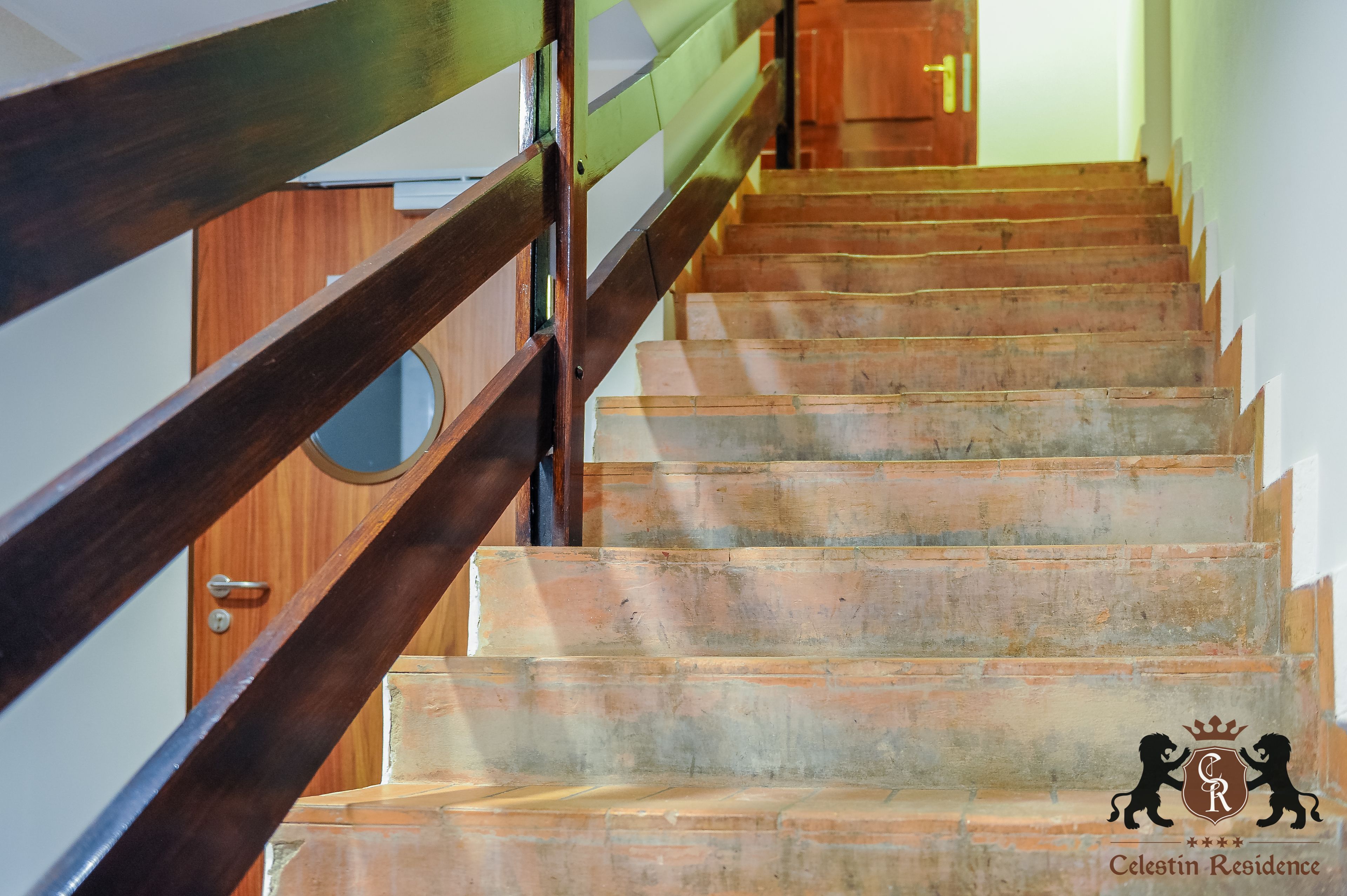 A wooden staircase with a metal railing, leading to a wooden door.