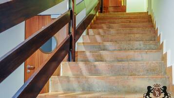 A wooden staircase with a metal railing, leading to a wooden door.