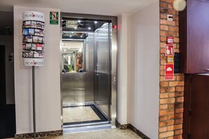 An elevator with a 'niceplace' advertisement, a brick wall, and emergency exit signs.
