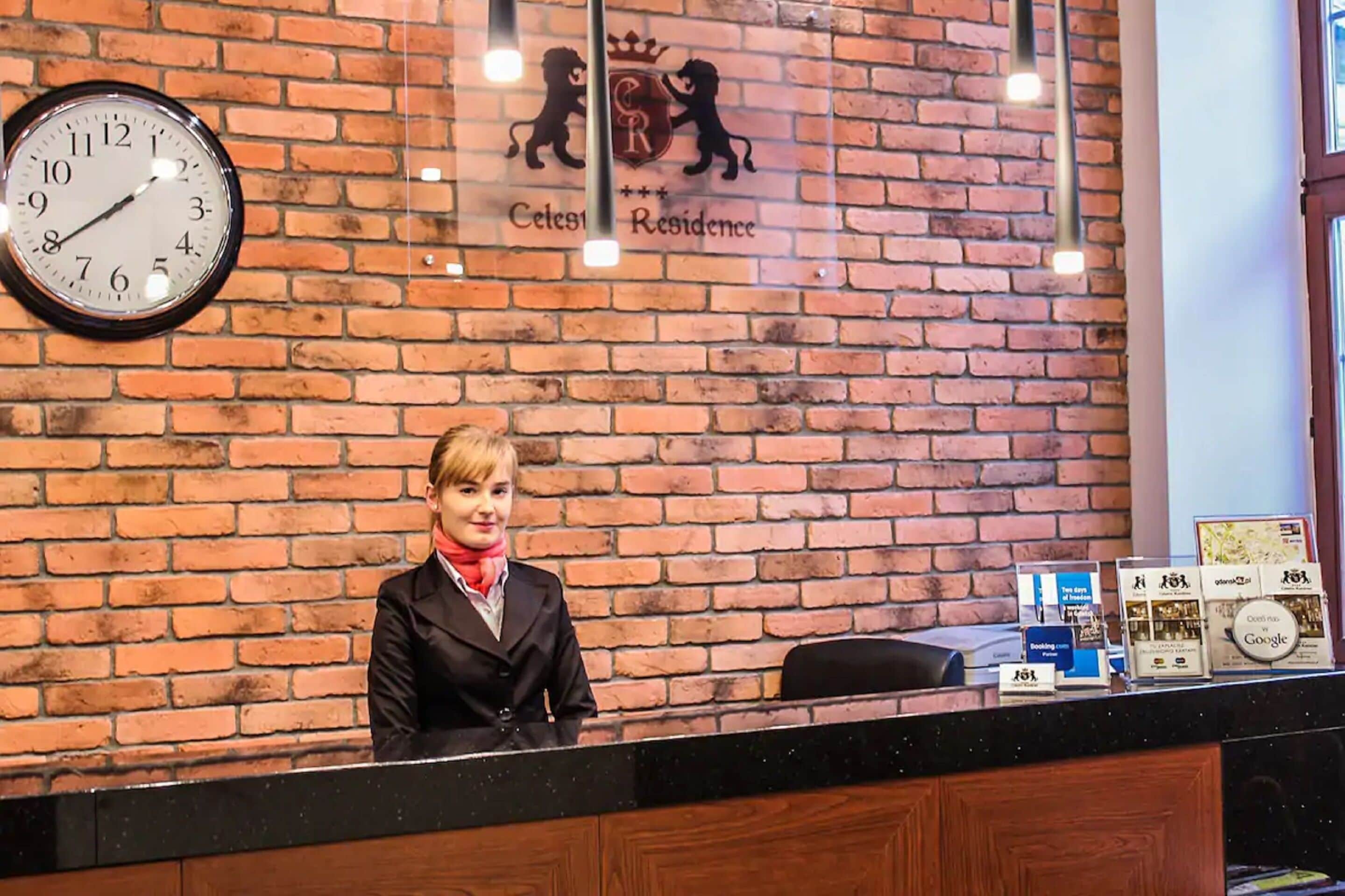 A reception desk with a clock, a logo, and various informational brochures.