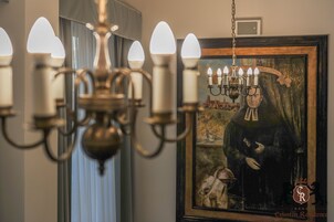 Un lampadario con più luci e un quadro incorniciato che raffigura una persona con un libro.