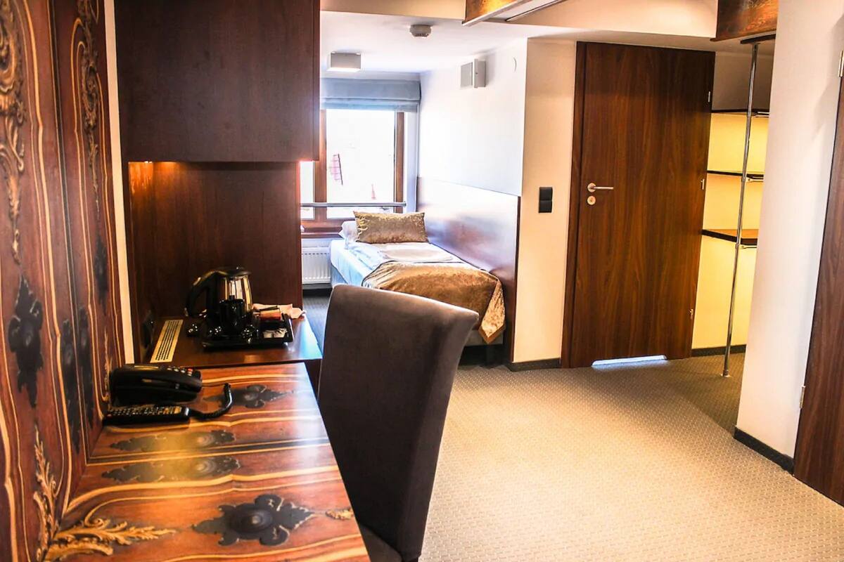 A hotel room with a bed, a desk with a telephone, and a chair.